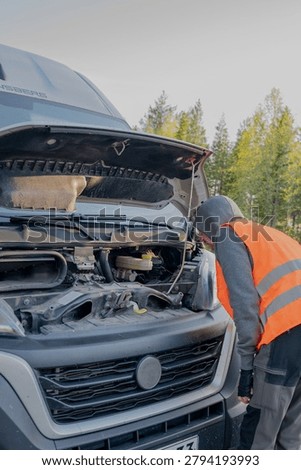 roadside assistance worker inspecting engine compartment of broken delivery van