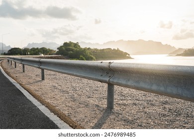 Roadside metal rail barrier structure which is installed on side of the road for protected the car accident. Transportation safety equipment object, selective focus.
