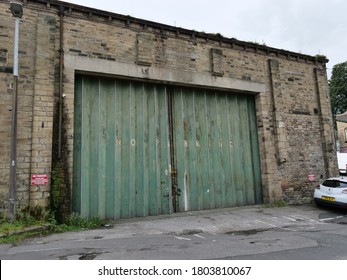 Roadside Stone Built Single Story Industrial Building Large Rusty Green Concertina Type Folding Double Doors With No Parking In White  Huddersfield Yorkshire England 27/08/2020 By Roy Hinchliffe