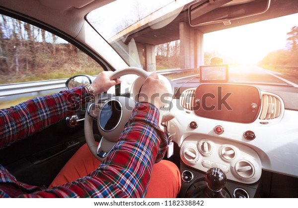 roadtrip - mans hands on the wheel and\
autobahn in the\
background\
