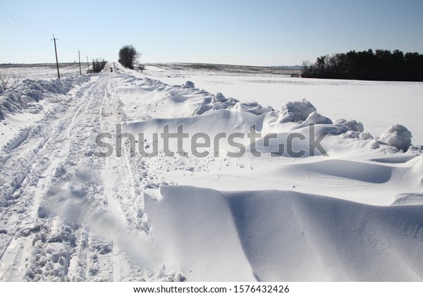 Roadway in Europe covered with thick layer of white\
snow on sunny winter day.  Drastic weather condition. Climate\
changes. Morning after snowfall all night. Driving on snow making\
travel hazardous. \
