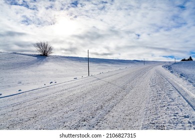 Roadway in winter with snow, gravel, gravel stones and snow poles