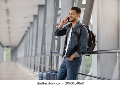 Roaming Abroad. Portrait Of Handsome Arab Man Talking On Cellphone In Airport, Happy Smiling Middle Eastern Guy Enjoying Phone Conversation While Waiting For Flight In Terminal, Copy Space