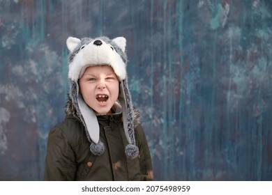 The Roar Of A Wolf. Child In A Wolf Hat On Gray Background, Outdoor. High Quality Photo