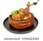 Roast beef dinner in a Yorkshire pudding meal with tender slices of roast beef, diced roasted potatoes and carrots isolated on a white background