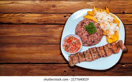 Roast beef dish with gallo pinto and pico de gallo, Roast beef with tomato and gallo pinto salad served on a wooden table, Plate with roast beef and rice served on a wooden table, Nicaraguan food