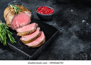 Roast Beef Fillet Tenderloin Meat On A Marble Board. Black Background. Top View. Copy Space