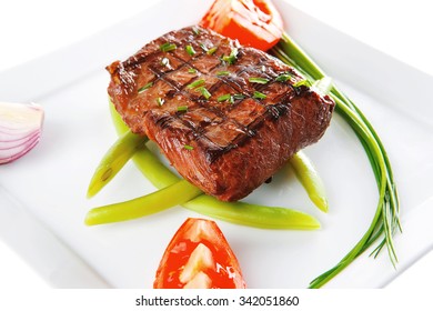 roast beef meat fillet entrecote served with tomato on white plate isolated over white background
