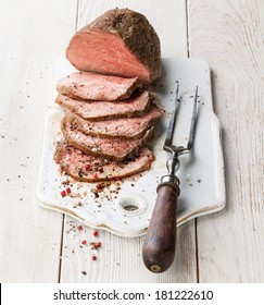 Roast Beef And Meat Fork On White Wooden Background