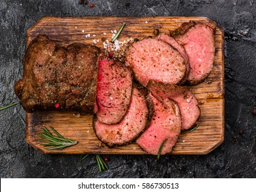 Roast beef on cutting board with salt and pepper. Top view. - Shutterstock ID 586730513