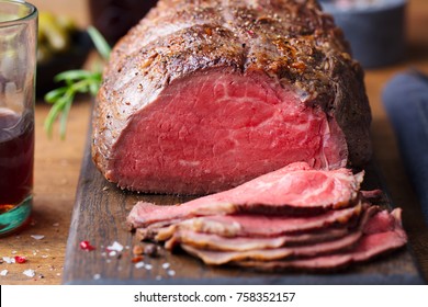 Roast beef on cutting board. Wooden background. Close up.