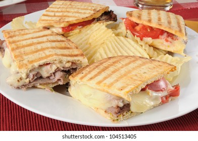 A Roast Beef Panini Sandwich With Potato Chips