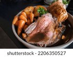 Roast beef slices on a plate with carrots, roast potatoes, a Yorkshire pudding and gravy, making a complete Sunday roast meal. 