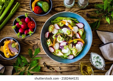 Roast Chicken Salad With Radish, Cucumber, Yellow Pepper And Leafy Greens Vegetables On Wooden Table 