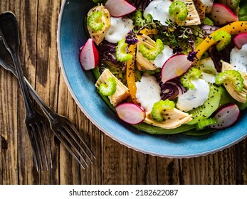 Roast Chicken Salad With Radish, Cucumber, Yellow Pepper And Leafy Greens Vegetables On Wooden Table 