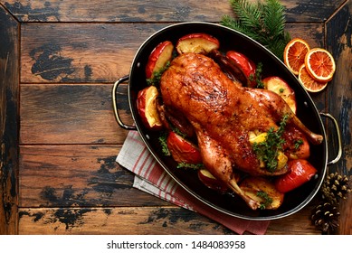 Roast goose stuffed with baked apples in a skillet on a dark wooden background, festive christmas recipe. Top view with copy space.
