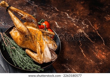 Roast guinea fowl with herbs and spices, cooked game bird. Dark background. Top view. Copy space.