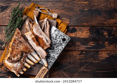 Roast lamb ribs, mutton spareribs, sliced meat on wooden board. Wooden background. Top view. Copy space.
