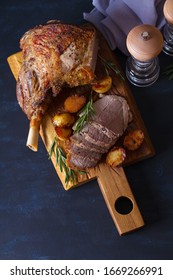 Roast Leg Of Lamb With Potatoes And Rosemary On Serving Wooden Board. View From Above, Top View