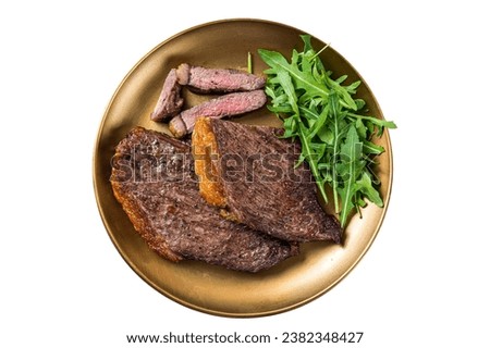 Roast picanha or top sirloin beef meat steak on a plate with arugula salad. Isolated on white background