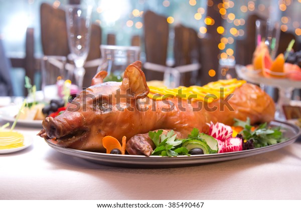 Roast pig.\
Roasted piglet with vegetables on\
platter