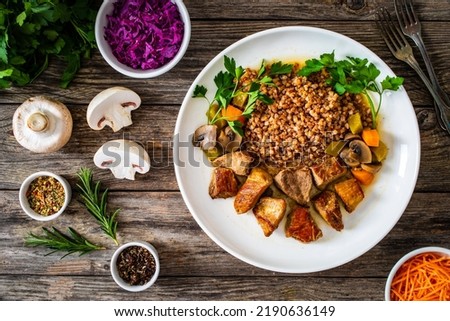 Roast pork with buckwheat groats, mushrooms and carrots served on wooden table 
