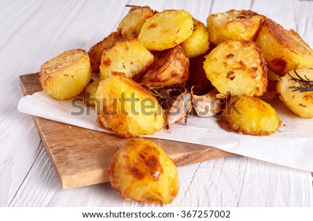 Roast potatoes seasoned with salt, garlic and provance herbs on wood background