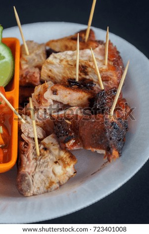 Roast ribs with chirmol and on a white plate. A woman taking a piece.