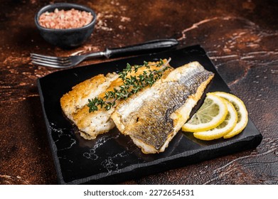 Roast sea bass fillet with lemon and thyme, seabass fish. Dark background. Top view.