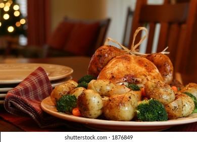 Roast Turkey, Potatoes, Onions, Broccoli And Carrots, Christmas Tree In Background.