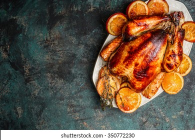 Roast Whole Turkey Or Chicken In Plate With Roasted Oranges On Dark Rustic Background, Top View