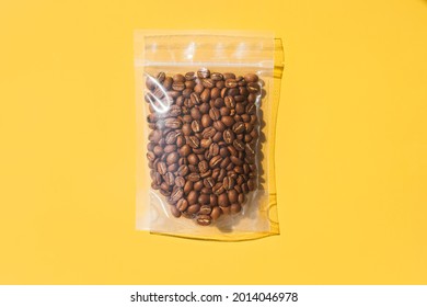 Roasted arabica coffee beans in blank transparent plastic bag with zipper on yellow background. Specialty and alternative sample coffee trendy concept. Space for text, mock up, top view, flat lay - Shutterstock ID 2014046978