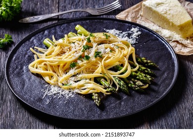 Roasted Asparagus Spears With Pasta Sprinkled With Shredded Pecorino Cheese And Parsley On Black Plate On Dark Wood Table, Horizontal View From Above, Close-up