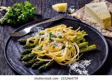 Roasted Asparagus Spears With Pasta Sprinkled With Shredded Pecorino Cheese And Parsley On Black Plate On Dark Wood Table With Cheese On Background, Close-up