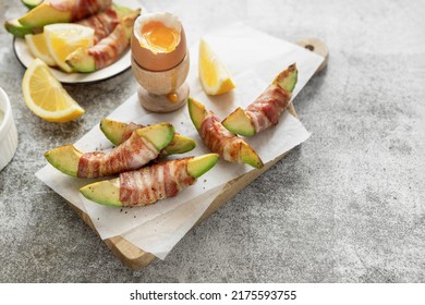 Roasted Avocado Slices Wrapped In Crispy Bacon And Soft Boiled Egg On Wooden Board; Low Carb High Fat Food, Ketogenic Diet Meal Idea