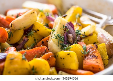 Roasted And Baked Root Vegetables In Rustic Tray With Fresh Thyme