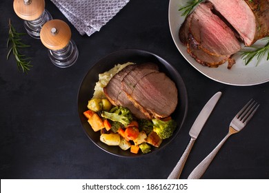 Roasted beef with herbs ovegetables on dark background. View from above, top studio shot