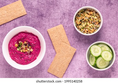 Roasted Beet Hummus with sprouted grains, cucumber and crispbread, top view.