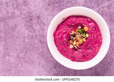 Roasted Beet Hummus with sprouted grains in a bowl, top view.