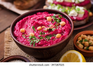 Roasted Beet Hummus with toast in a ceramic bowl on a wooden background