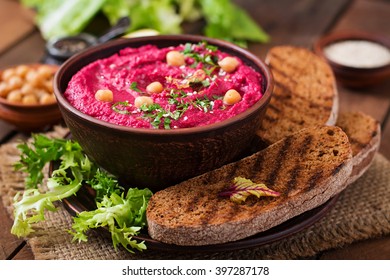 Roasted Beet Hummus with toast in a ceramic bowl on a wooden background