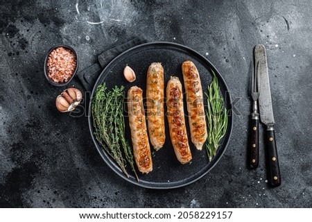 Roasted Bockwurst pork meat sausages in a plate. Black background. Top view