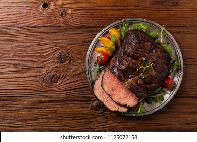 Roasted brisket. Rustic style, natural wooden background. Dark style. Top view. Flat lay. 
