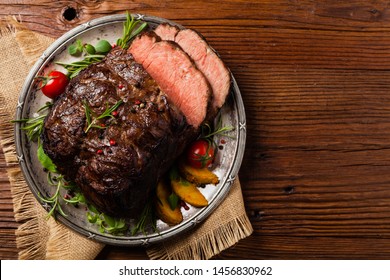 Roasted brisket. Rustic style, natural wooden background. Dark style. Top view. Flat lay. 