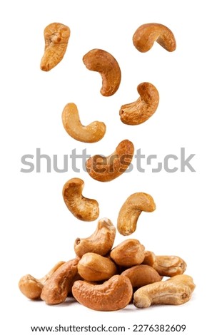 Roasted cashew nuts fall on a pile close-up on a white background. Isolated