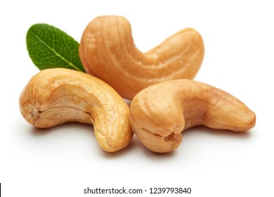 Roasted cashew nuts with green leaves isolated on white background. Macro, studio shot