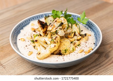 Roasted Cauliflower and Hummus dish with coriander leaf in a wooden table - Shutterstock ID 1721775400