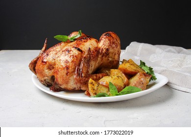 Roasted Chicken With Fried Potato On Plate On Grey Table With Napkin, Black Background. Side View.