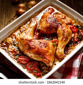 Roasted chicken leg quarters  with herbs and spices served in a baking dish close up view