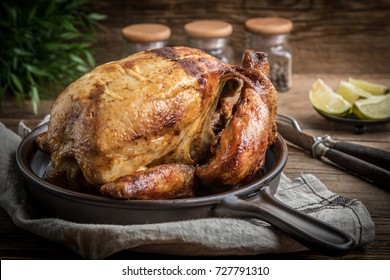 Roasted chicken on plate on wooden table.